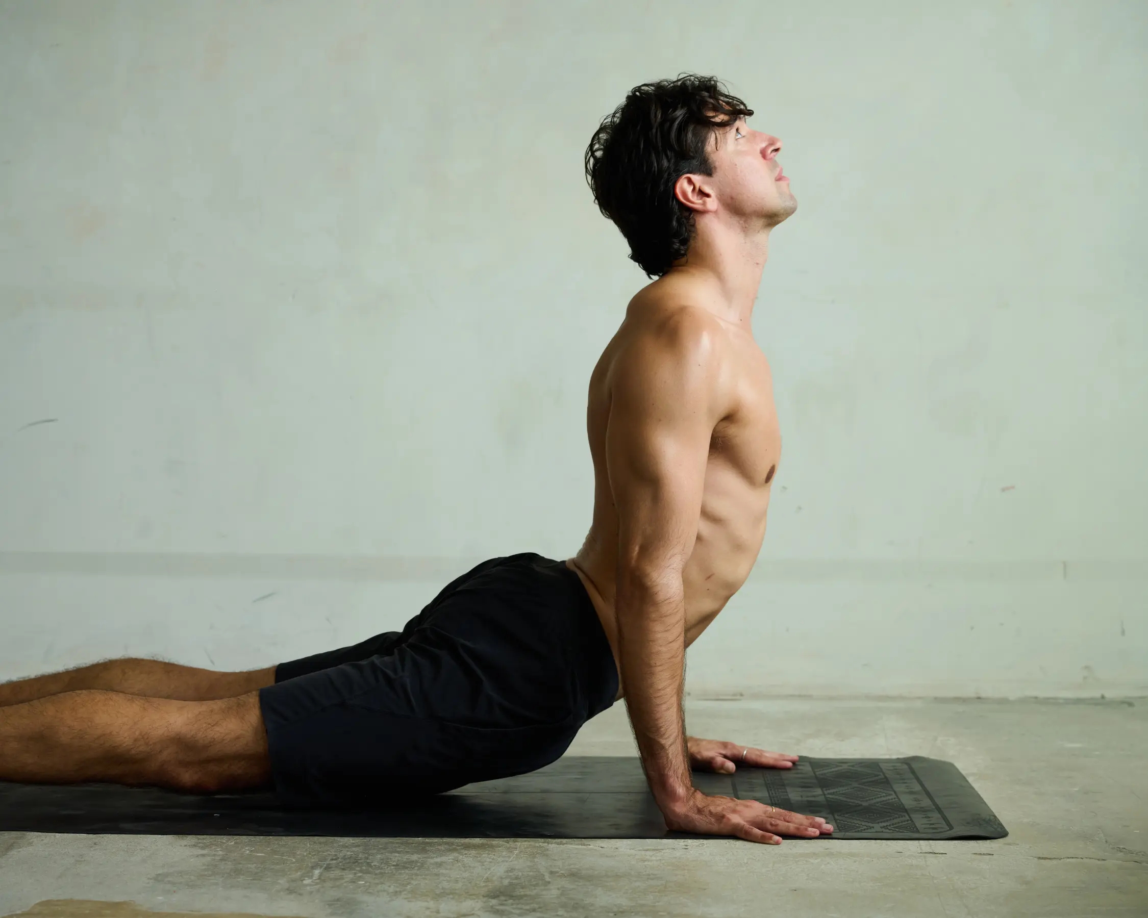 Ruben moving through upward dog on a yoga mat